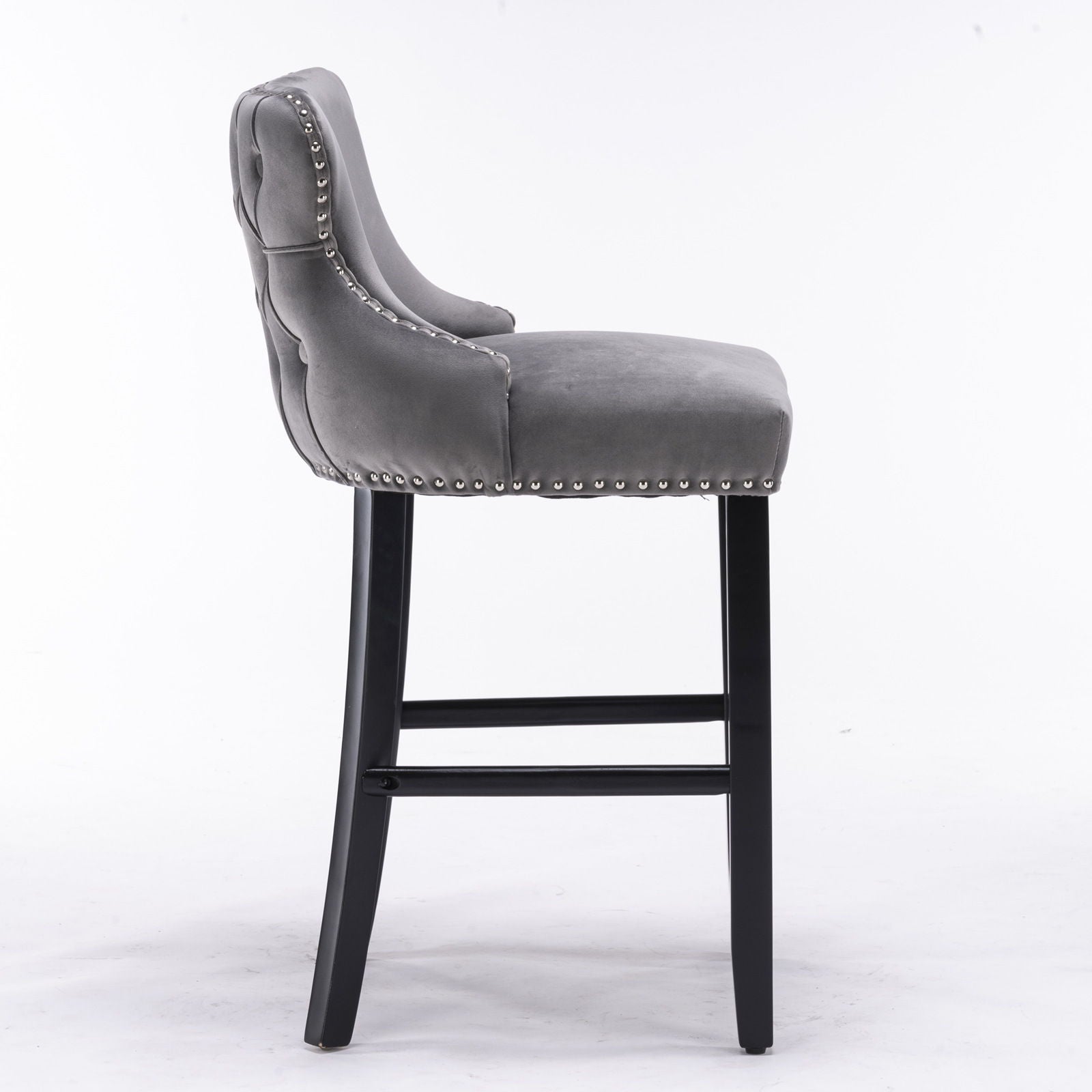 A set of 2 contemporary velvet wing-back barstools with button tufting, chrome nailhead trim, and wooden legs, shown in profile on a white background.