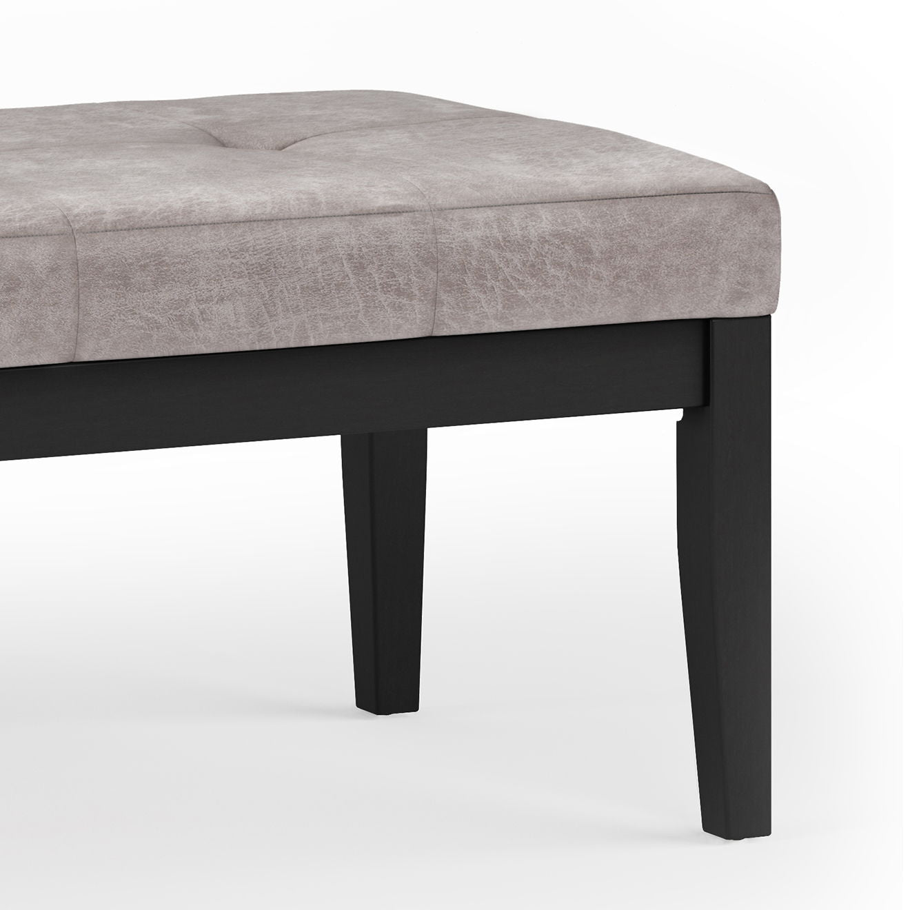 A close-up of the Lacey - Upholstered Tufted Ottoman Bench features a light gray cushioned seat and black wooden legs, photographed against a white background.