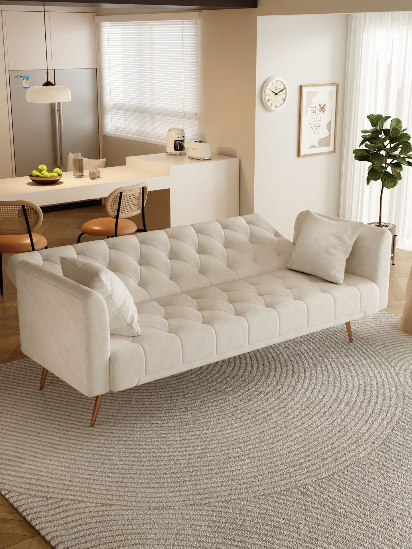 A modern living room features a Convertible Double Folding Living Room Sofa Bed with two pillows on a round textured rug, near a kitchen area with bar stools, refrigerator, and countertop with fruit and appliances in soft natural light.