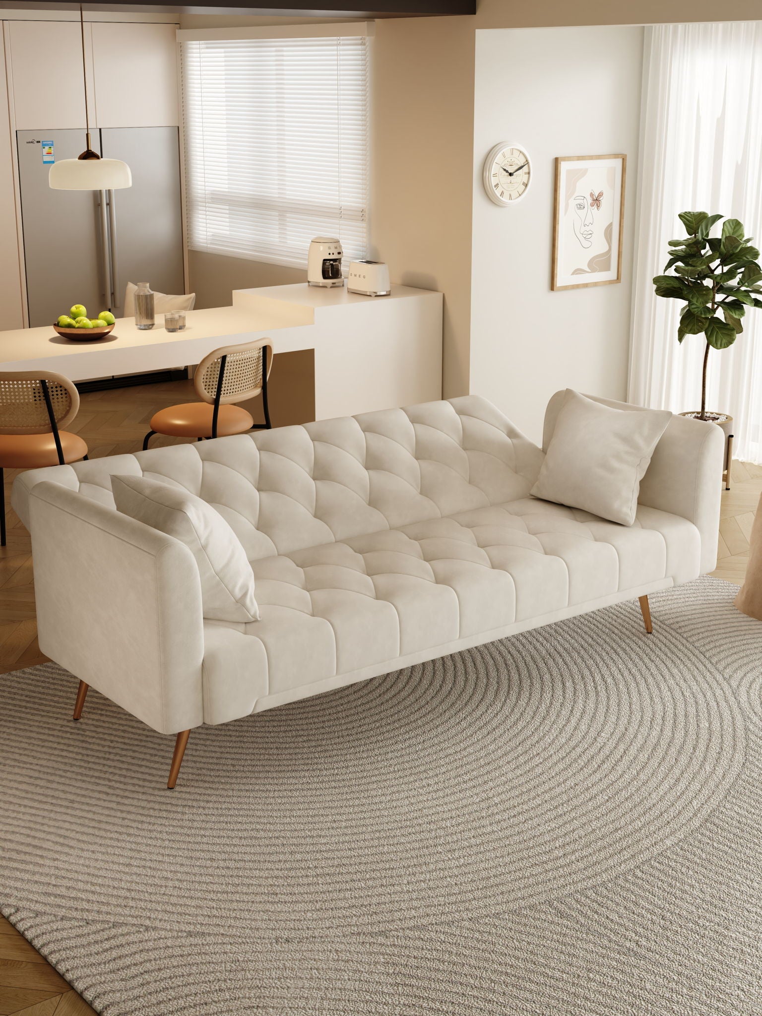 A modern living room features a Convertible Double Folding Living Room Sofa Bed with two pillows on a round textured rug, near a kitchen area with bar stools, refrigerator, and countertop with fruit and appliances in soft natural light.