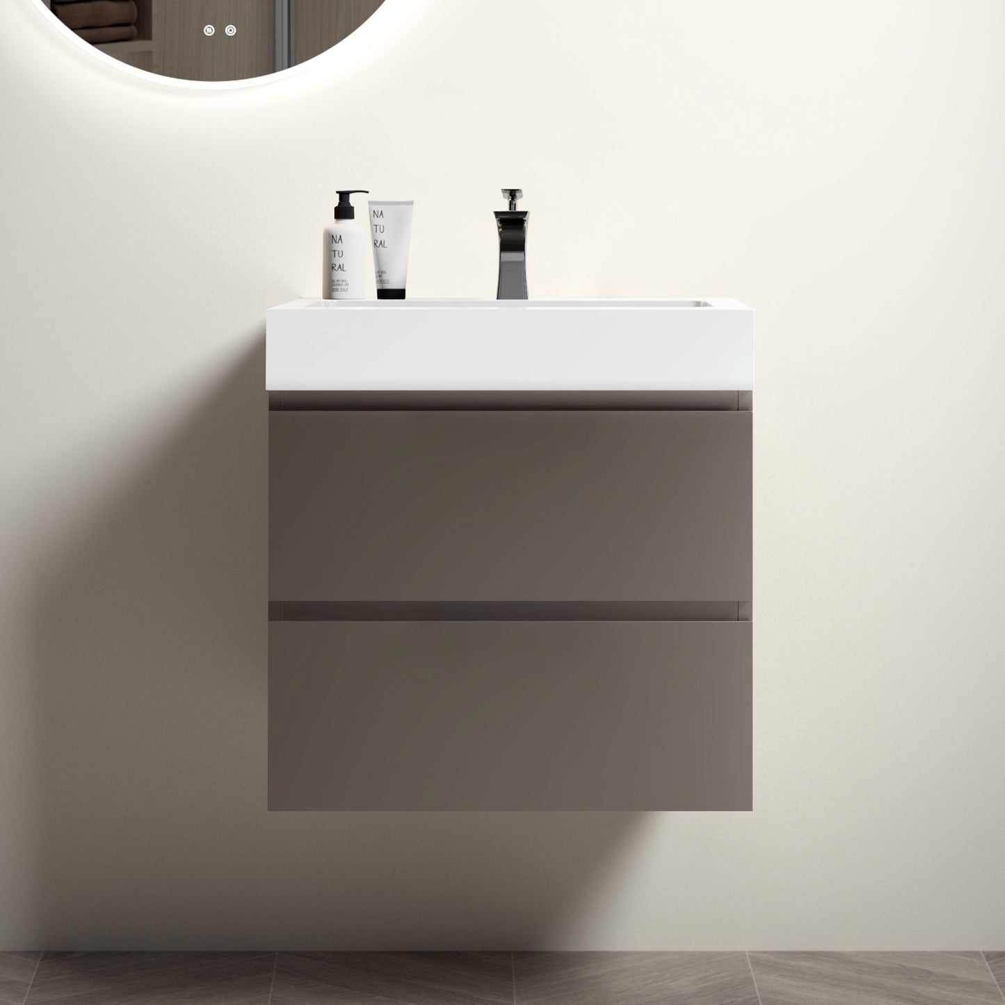 The Alice Bathroom Vanity features a modern, wall-mounted design with large gray drawers and a one-piece white basin, set against a light wall with a round mirror above. Drain and faucet not included.