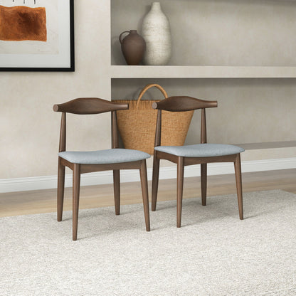 The Destiny - Modern Dining Chairs (Set of 2) with light gray seats are arranged on a textured beige rug, complemented by a large woven basket and decorative vases displayed on shelves against a light wall.