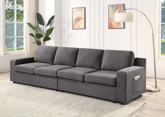A modern living room featuring the Waylon Linen Sectional Sofa, a light rug, floor lamp, two abstract wall art pieces, a large plant, and sunlight streaming in through the window.
