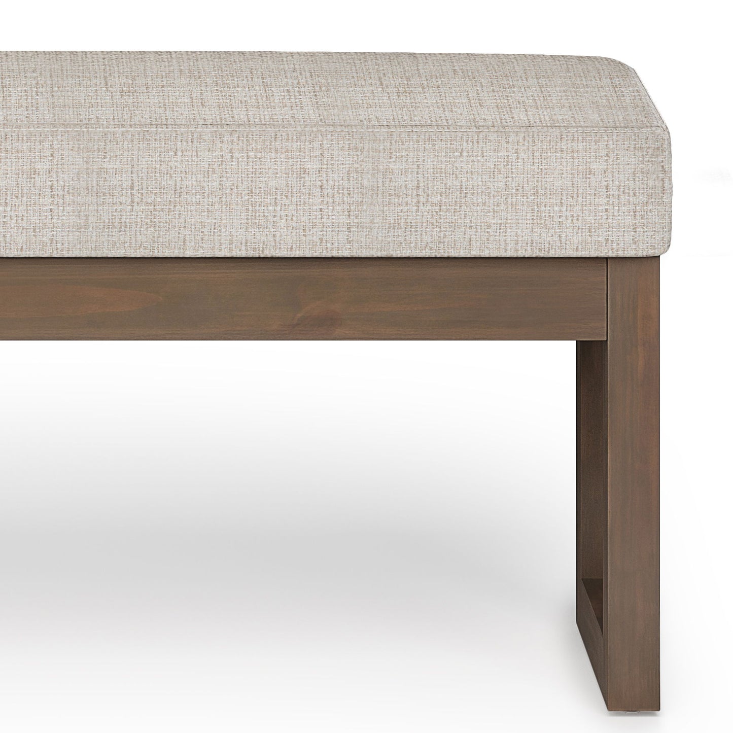 A close-up of the Milltown - Upholstered Ottoman Bench, featuring a light beige cushion and wooden square-leg base, set against a white background.