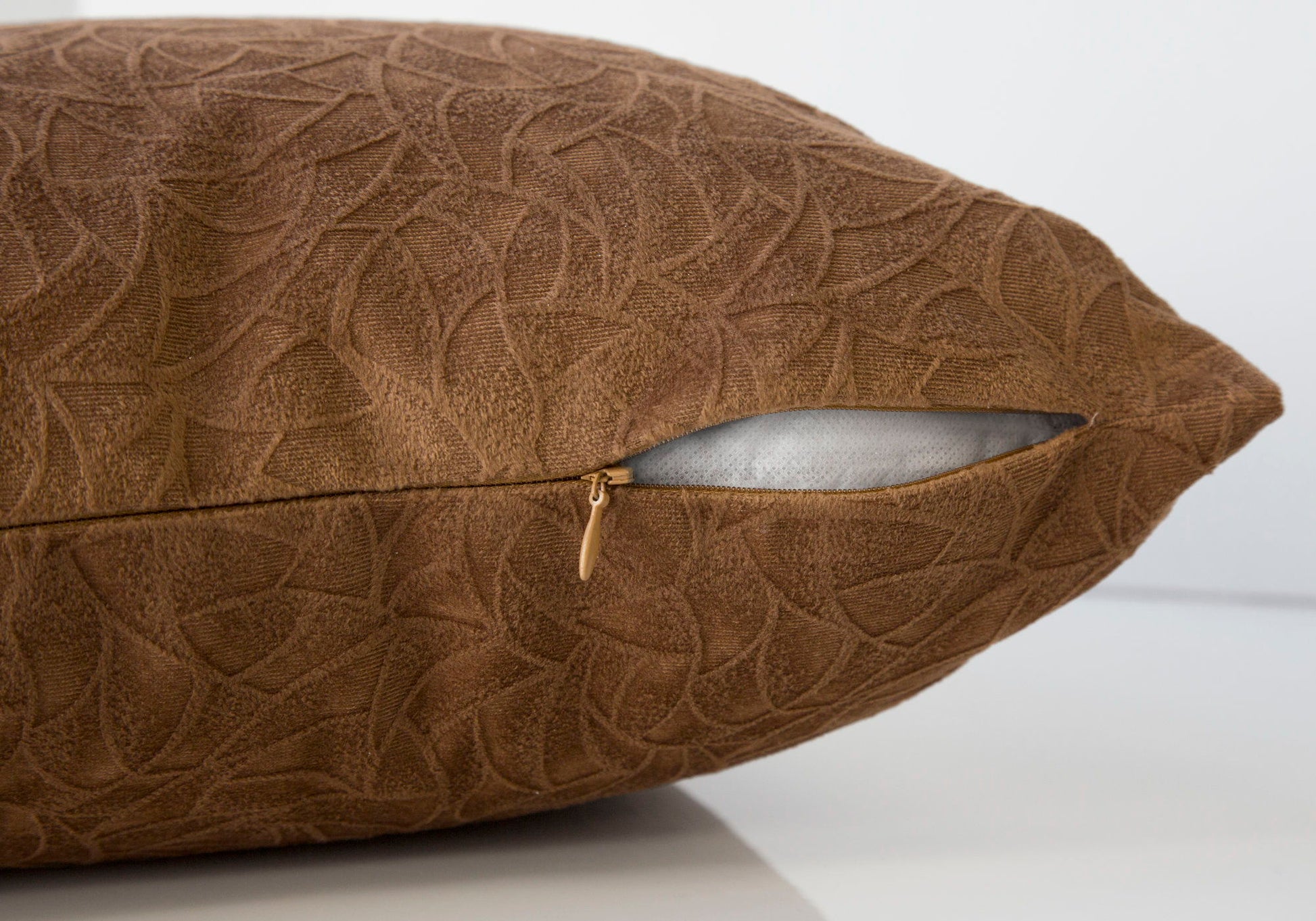 A close-up of the Pillow Square, Decorative Throw, with its gold zipper partially open to show the hypoallergenic insert. The brown patterned pillow rests on a white surface against a light background.