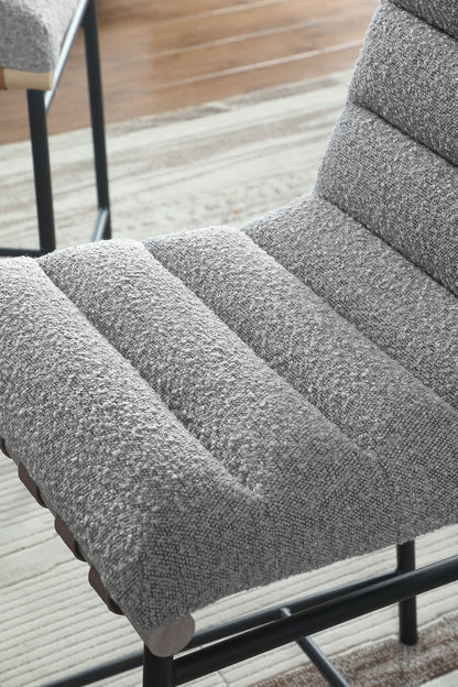A close-up of the Lahni 17" Boucle Fabric Counter Height Chair in textured gray upholstery with horizontal stitching, shown on a striped rug over a wooden floor.
