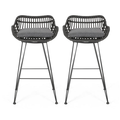 The Outdoor Rattan Bar Chair With Metal Legs features a woven rattan-style back, armrests, black metal legs, and dark gray seat cushions. Two chairs are shown facing forward on a white background.