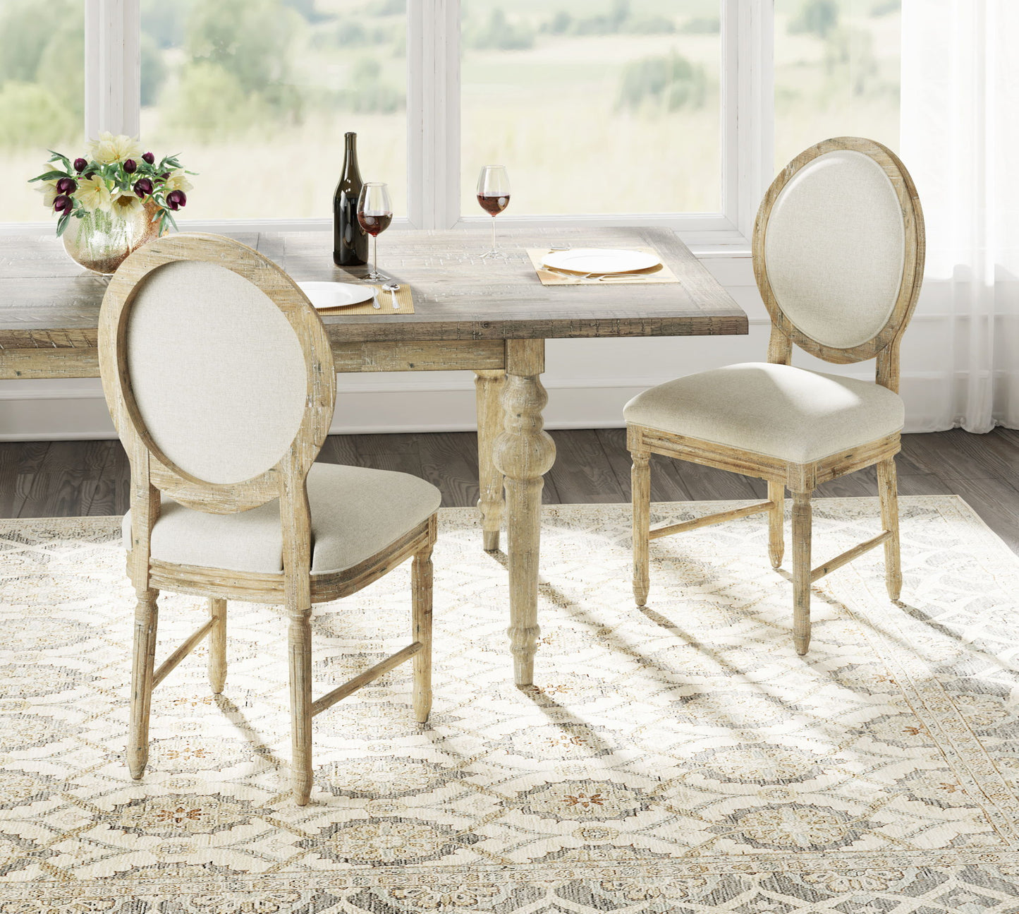 A rustic wooden dining table set with the Ludin Upholstered Dining Chairs (Set of 2, Brown), a vase of flowers, wine bottle, two glasses of red wine, and two plates in a bright room with large windows and scenic outdoor views.