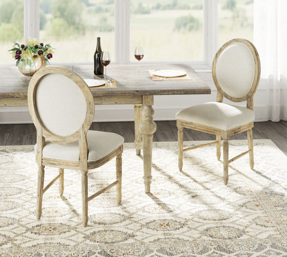 A rustic wooden dining table set with the Ludin Upholstered Dining Chairs (Set of 2, Brown), a vase of flowers, wine bottle, two glasses of red wine, and two plates in a bright room with large windows and scenic outdoor views.