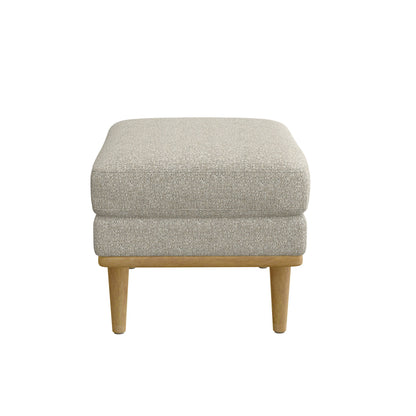 The Revel Chair Ottoman in tan is a square, upholstered piece with wooden legs, shown from the front against a white background.