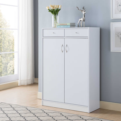 A white shoe storage cabinet with five shelves and two drawers, holding up to 15 pairs of shoes, stands against a light gray wall near a window with white curtains. A vase of yellow tulips, books, and a silver deer figurine decorate its top.