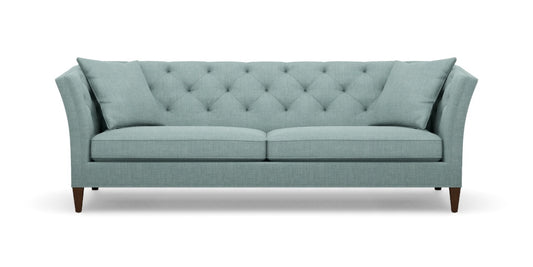 The Shelton 98" Sofa boasts a light teal color with tufted upholstery, featuring an angled backrest and cushions. Its wooden legs and contemporary design offer a stylish and comfortable two-seat seating option.