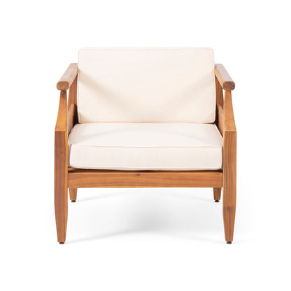 The Outdoor Club Chair With Recessed Arms And Cushions features a minimalist wooden frame, angled legs, and light beige seat and backrest cushions, shown against a white background.