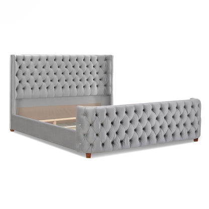 The Brooklyn Tufted Panel Bed features a luxurious gray upholstered frame with a tall, diamond-tufted headboard and matching footboard, both accented with button details and short wooden legs.