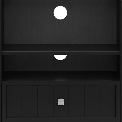 The Bedford Handcrafted Tall TV Media Stand is a black wooden unit with a bottom drawer featuring a square silver knob and two circular cable management holes in the back—one in the upper section and one in the middle.