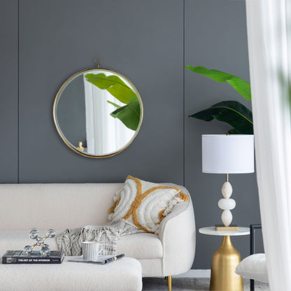 A modern living room with a white sofa, decorative pillow, gold side table with white lamp, green leafy plants, and a Round Mirror—Circle Mirror With Iron Frame—for living room, bedroom vanity, entryway, or hallway hung on a gray wall.