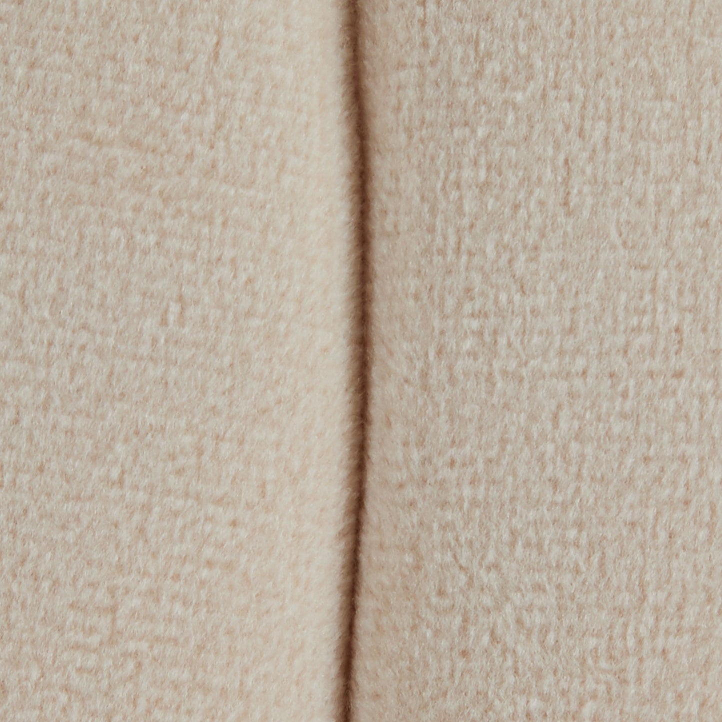Close-up of the Braided - Versatile Round Ottoman shows its soft, beige, textured fabric with a vertical seam running down the center.