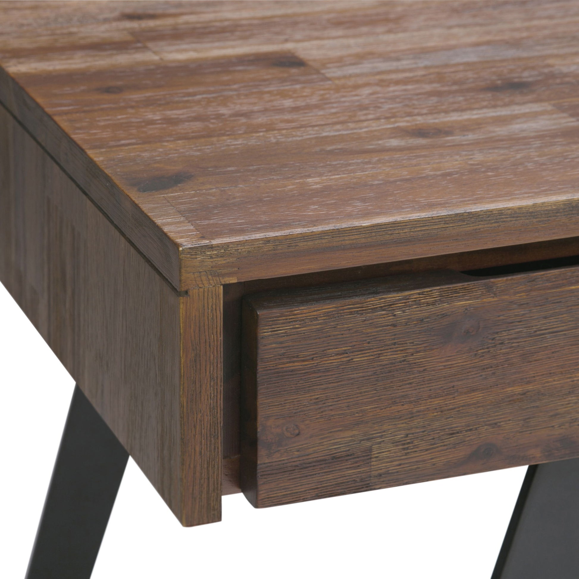 Close-up of the Lowry - Handcrafted Desk’s corner with a partially open drawer. It features a rustic finish, visible wood grain, and sits on angled black metal legs.