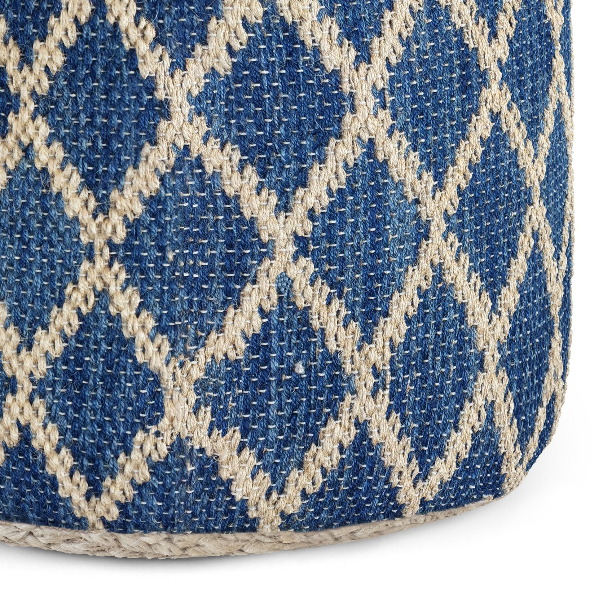Close-up of the Edgeley - Handcrafted Round Pouf, featuring coarse woven fabric with a blue background and a cream diamond lattice pattern. The prominent stitches create a decorative, textured surface.