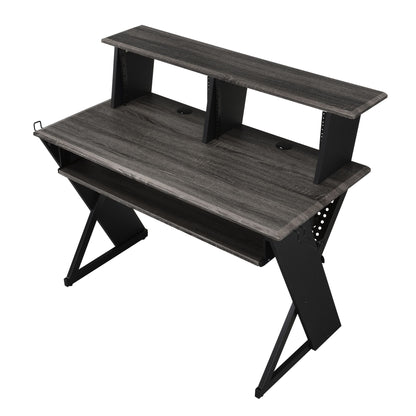The Humanity - Music Desk - Black features a modern, minimalist design with dark wood, X-frame black metal legs, a raised monitor shelf, lower storage shelf, and cable management holes—perfect for compact workspaces.