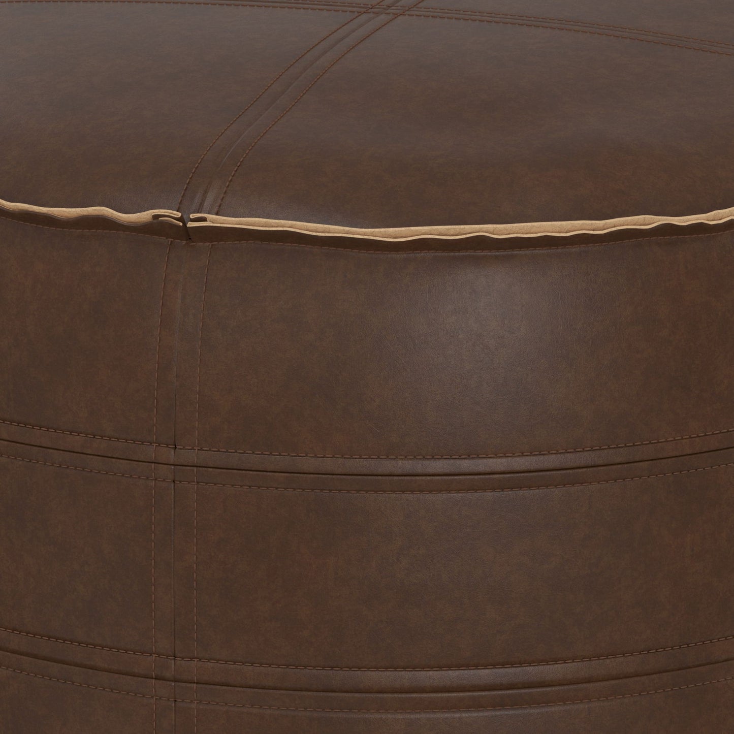 Close-up of the Brody - Round Pouf, featuring brown leather with visible stitching and a seam along the top edge. The leather texture and precise stitch alignment are clearly displayed.