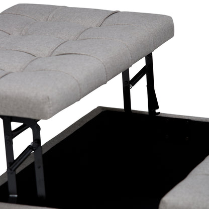 A close-up of the Harrison Upholstered Coffee Table Storage Ottoman shows its gray tufted cushioned top lifted, revealing hidden storage inside and a visible hinged metal mechanism supporting the lid.