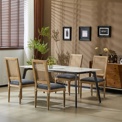 A modern dining room with a rectangular table, four French Country Dining Chairs with rectangular cane backrests and smooth upholstered seating, a potted plant, and framed art on a beige wall. Sunlight streams through window blinds, casting shadows.