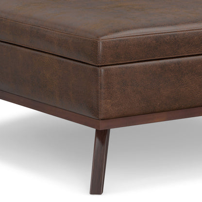 Close-up of the corner of the Owen Multifunctional Square Coffee Table Storage Ottoman, featuring brown leather upholstery, a wooden frame, and tapered wooden legs against a white background.