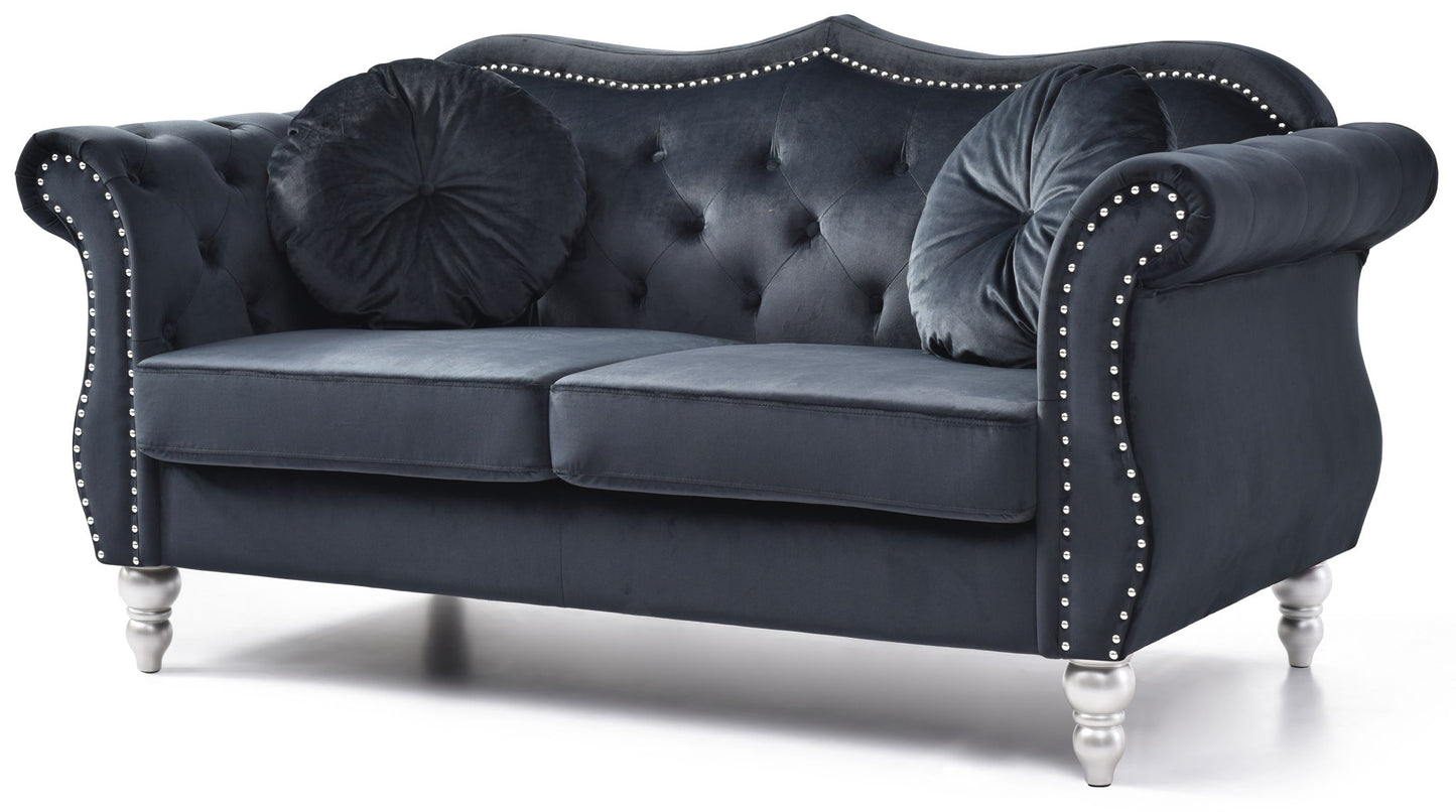 The Stylish Flared Arm Loveseat features a dark blue velvet finish, tufted back, silver stud accents, curved arms, two round pillows, and stands on four short silver legs.