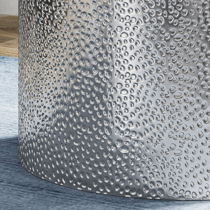 Close-up of the Modern Round Accent Table with a hammered, metallic surface reflecting light, placed on a light blue rug beside a wooden surface.