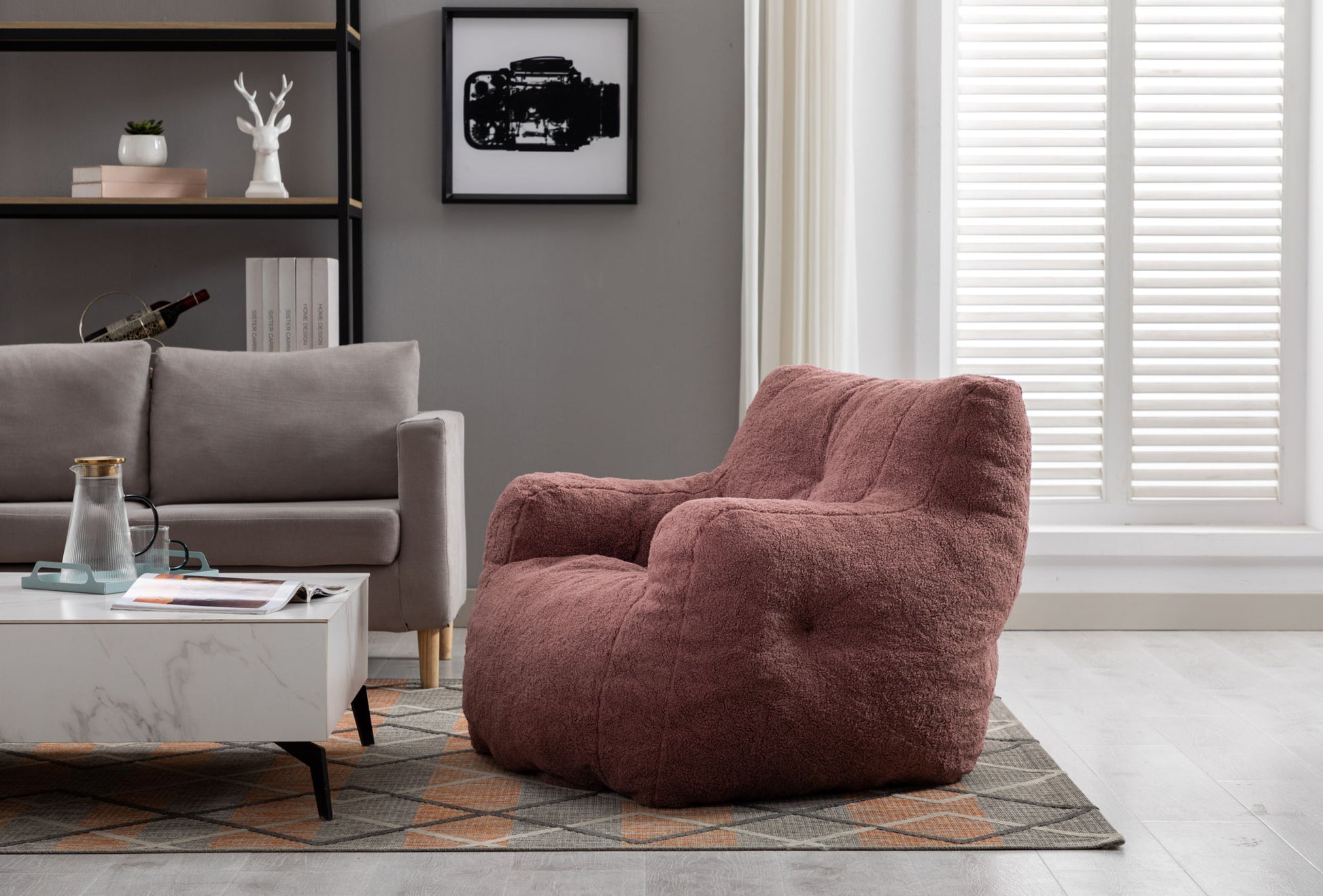 A Soft Teddy Fabric Tufted Foam Bean Bag Chair sits beside a light gray sofa and a marble coffee table in a modern living room with a geometric rug, wall art, and white shutters letting in natural light.