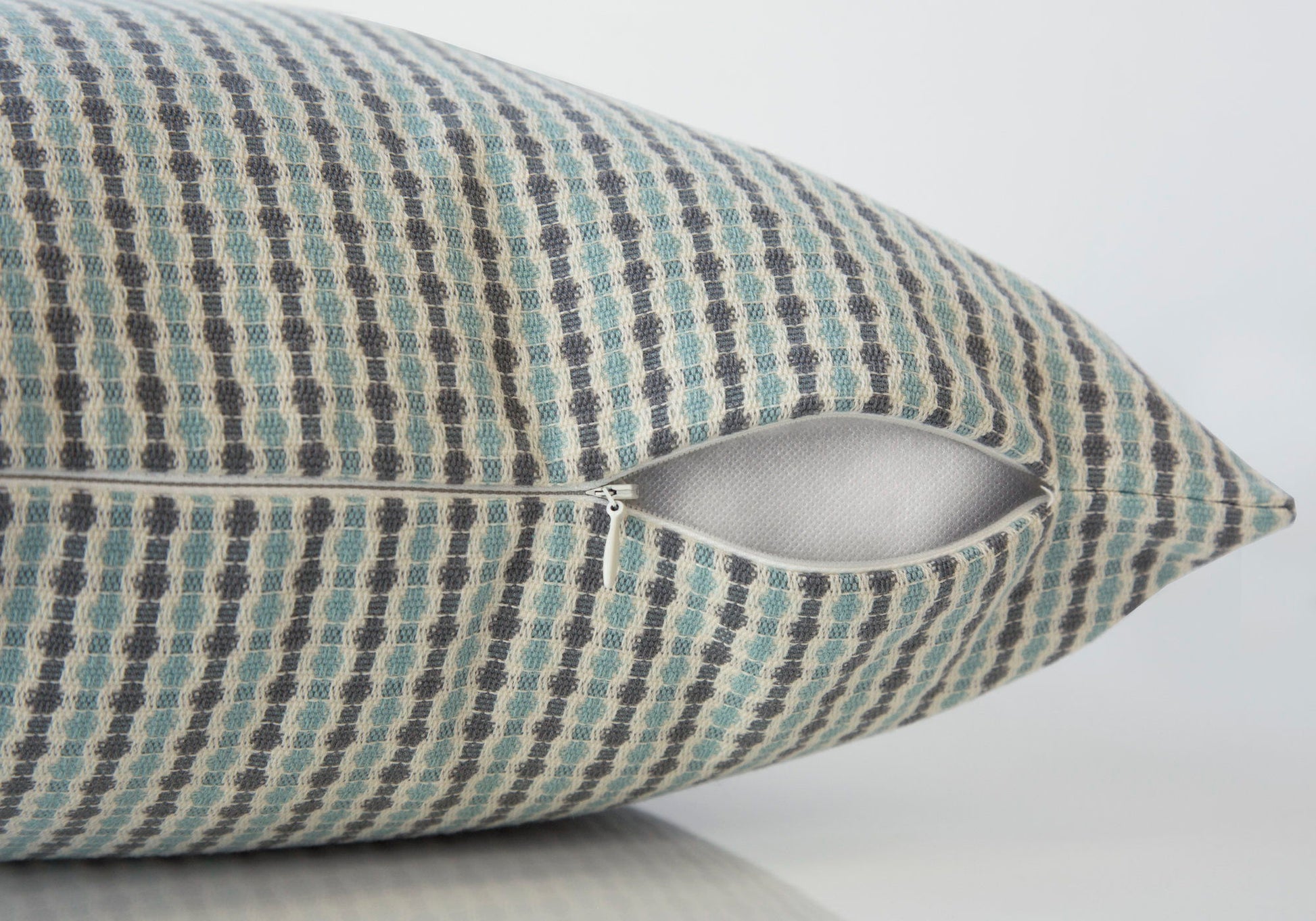 A close-up of a Square Decorative Throw Pillow, hypoallergenic with a blue and beige checkered cover, shows its partially open zipper and included white insert. Background is plain and light-colored.
