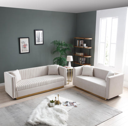Modern living room with a 2-piece Contemporary Vertical Channel Tufted Velvet Sofa Loveseat set (includes 4 pillows), a light rug and fur throw, small lamp side table, potted plant, wall art, bookshelf, and window with white shutters.