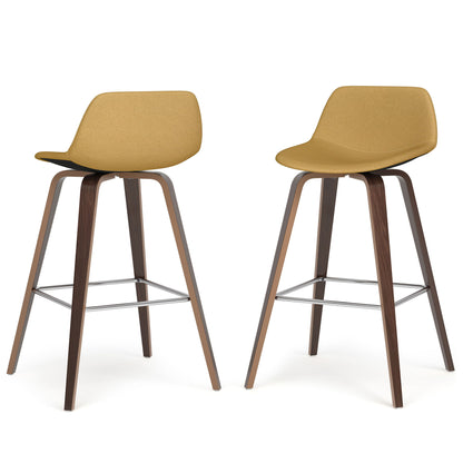 The Randolph Bentwood Counter/Bar Height Stool (Set of 2) features mustard yellow upholstered seats, curved backs, and angled wooden legs with metal footrests, shown on a white background.