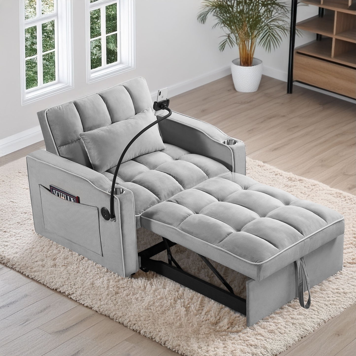 A Convertible Sleeper Chair Sofa Bed with multi-pockets and adjustable pull-out design sits in a bright room with wood flooring, large windows, a potted plant, and shelving unit—perfect for living rooms or small spaces.