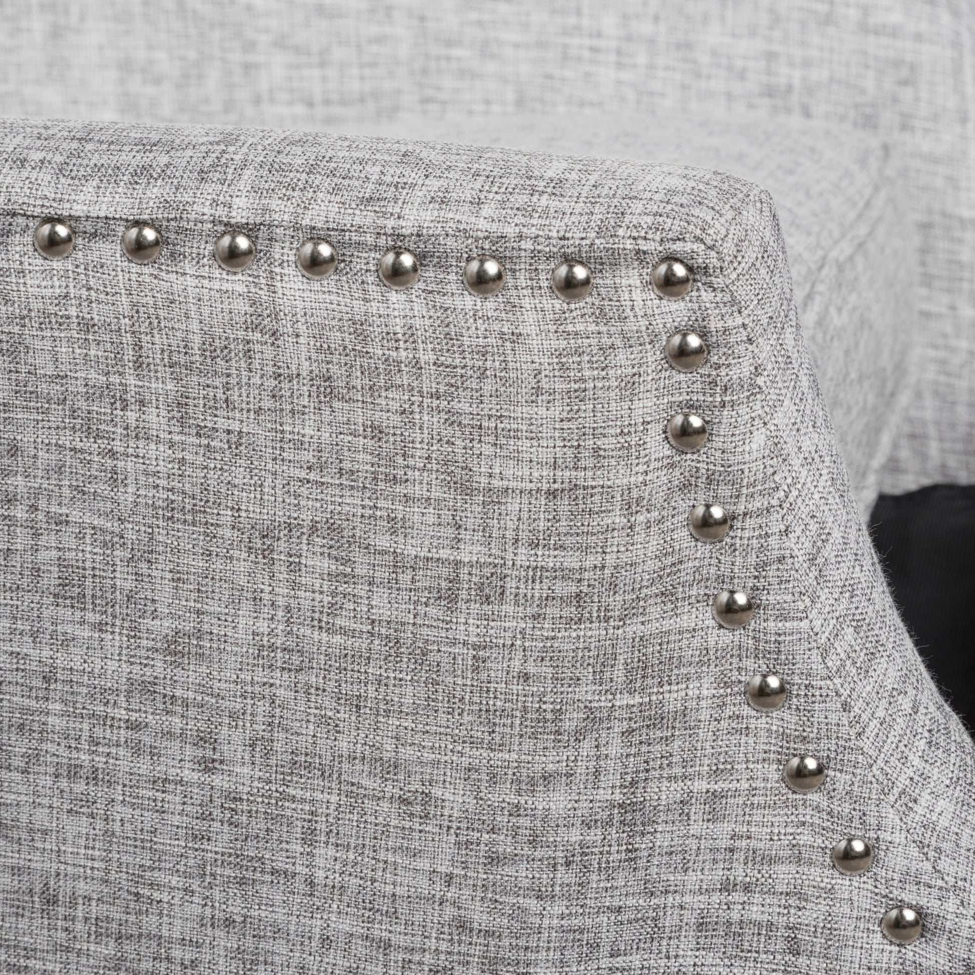 Close-up of the Westeros Wing Back Fabric Upholstered Recliner in light gray, showcasing its textured fabric and a row of silver nailhead trim along the curved armrest.