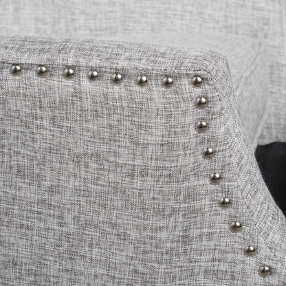 Close-up of the Westeros Wing Back Fabric Upholstered Recliner in light gray, showcasing its textured fabric and a row of silver nailhead trim along the curved armrest.