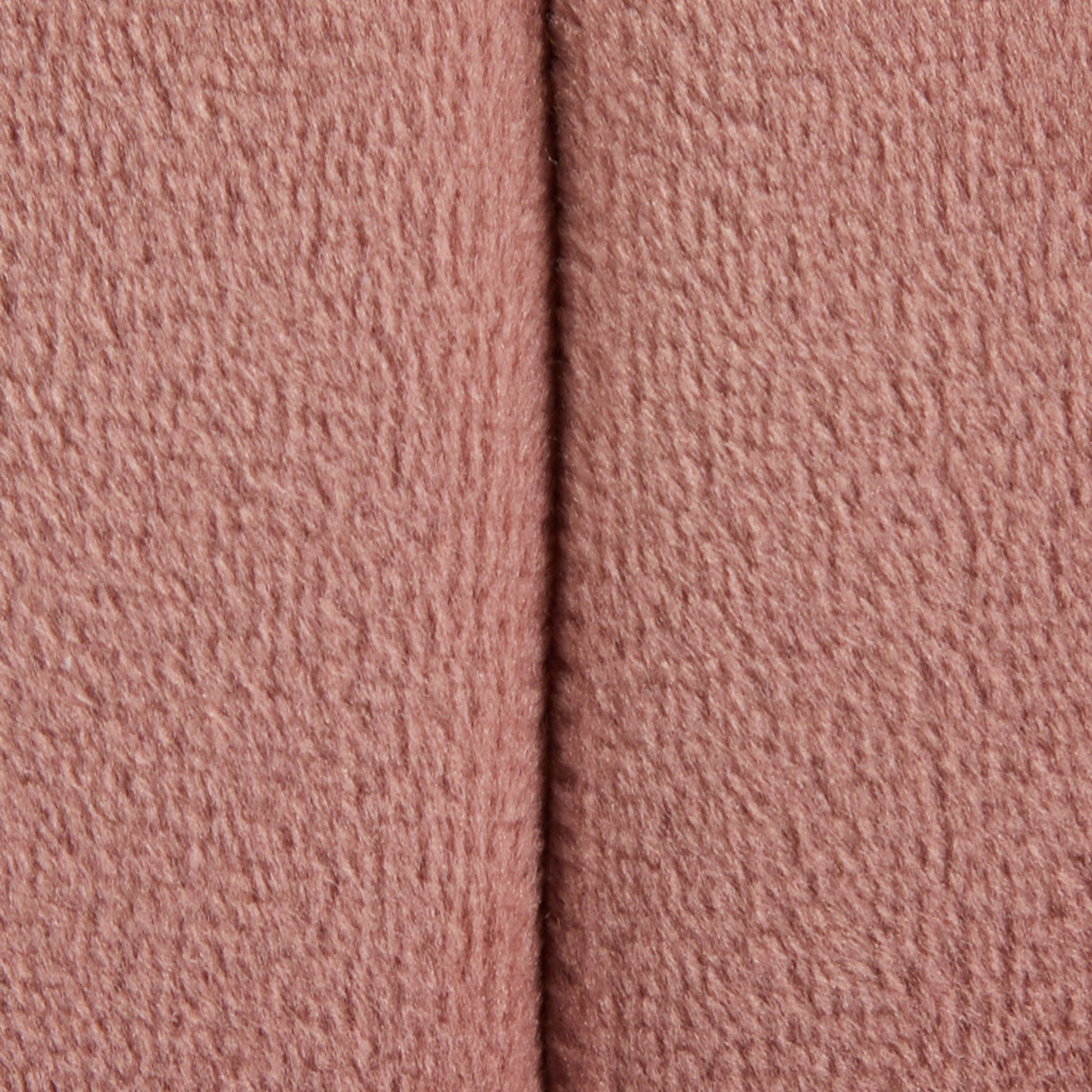 Close-up of the Braided - Versatile Round Ottoman shows its soft, textured pink fabric with a vertical seam running down the center.