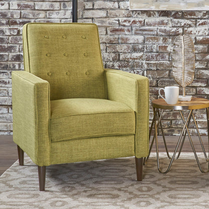 A Mid-Century Modern Recliner With Button Tufted Waffle Stitch sits beside a small round side table with a white mug and metallic decorative leaf, set against a brick wall background on a patterned rug.