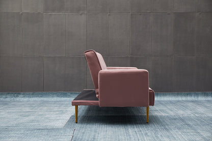 The Comfort Compact Design Sofa Bed, featuring a modern pink look with gold legs, is shown from the side on a light blue textured floor in front of a dark gray tiled wall.