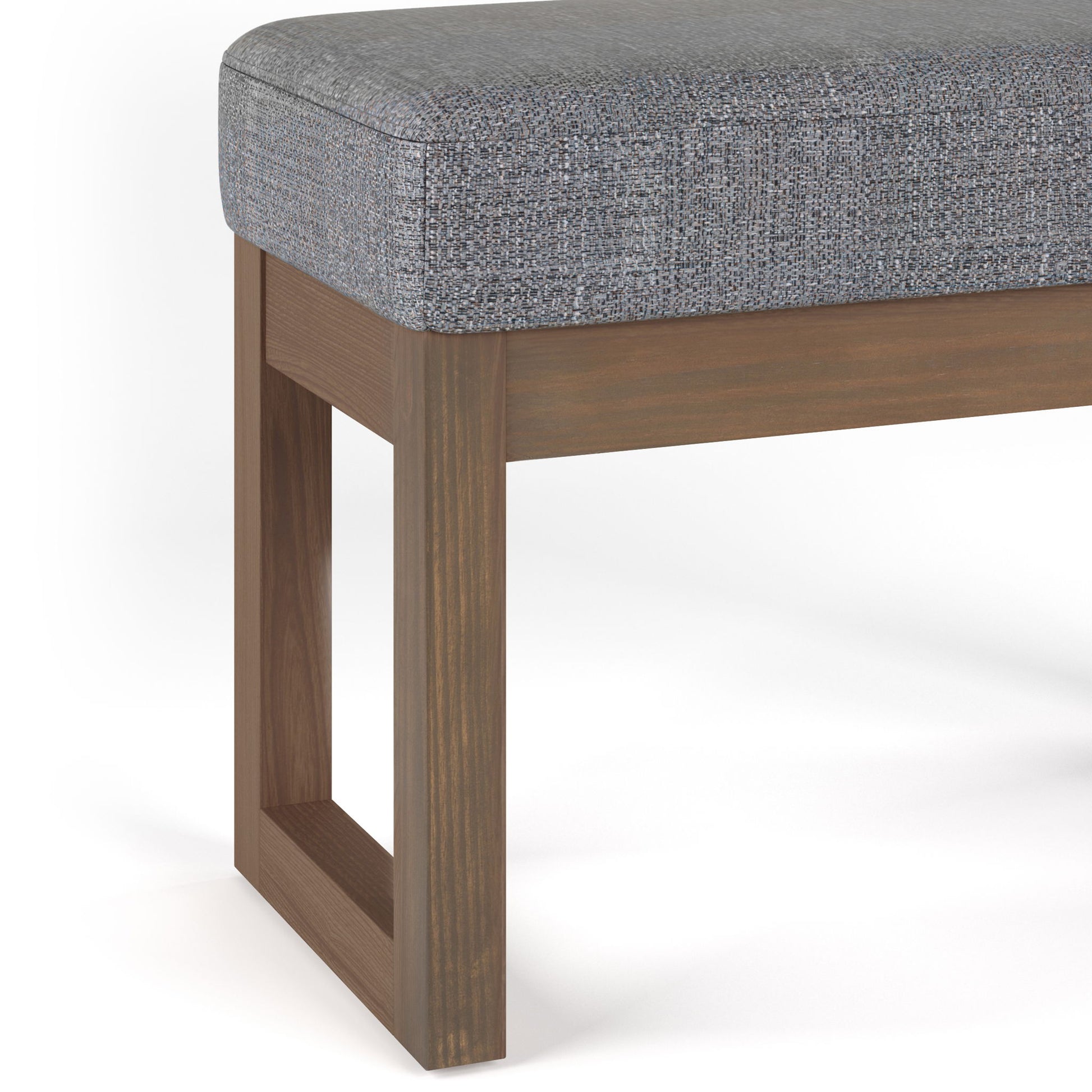 A close-up of the Milltown Upholstered Ottoman Bench, showcasing its gray cushion, wooden legs, and modern open rectangular design.