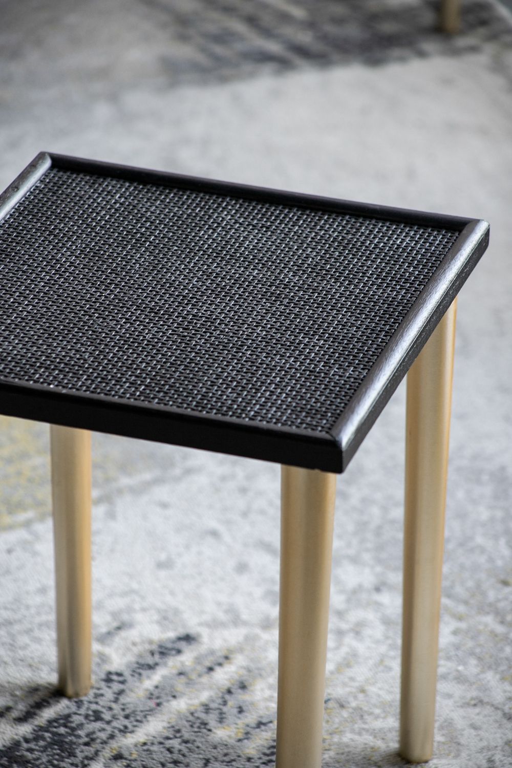 A set of three side tables featuring black, textured rectangular tops and four light wood legs, displayed on a patterned surface. Product: Side Tables (Set of 3) - Black / Gold.