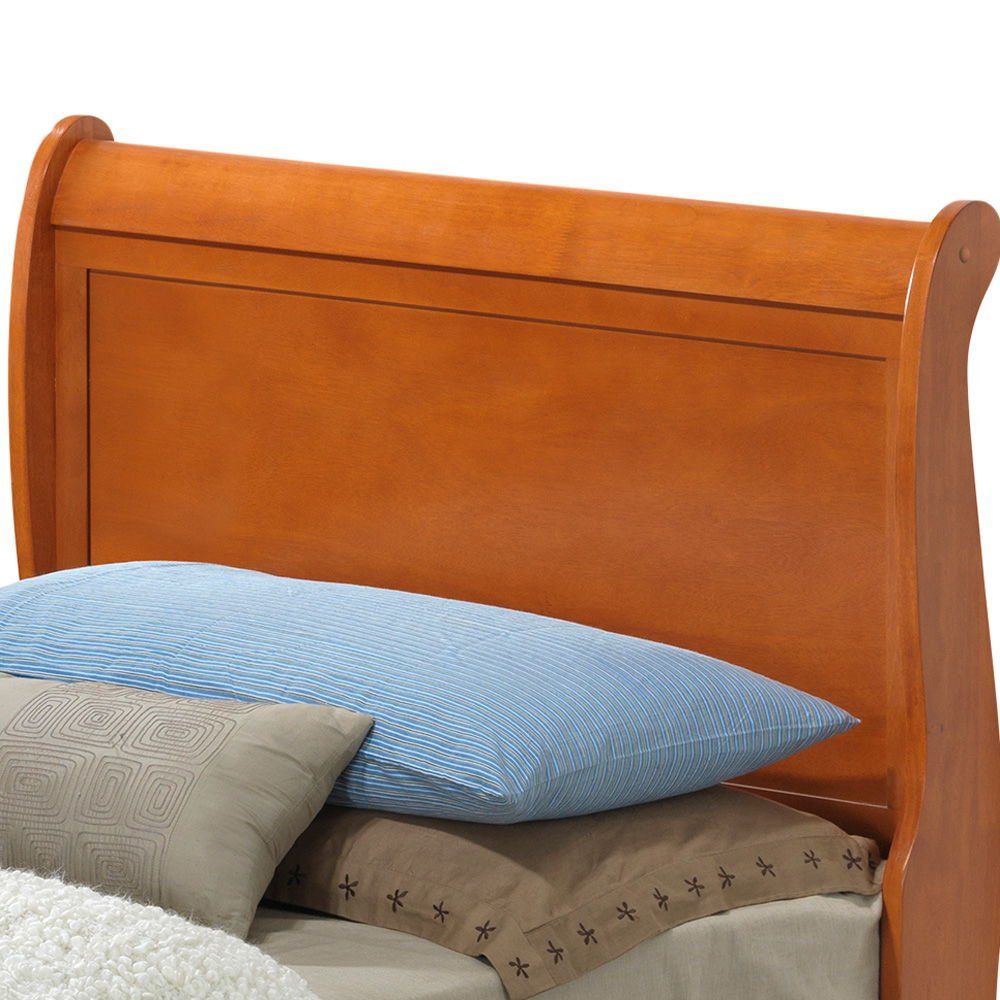 The Panel Sleigh Bed features a wooden sleigh-style headboard in a warm brown finish, paired with blue and beige pillows and neutral bedding.