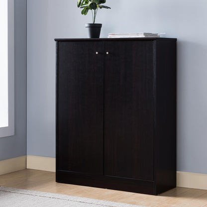 A Shoe/Storage Cabinet With Two Doors Five Shelves stands against a light blue wall, topped with a small potted plant and magazines. The floor beneath is light wood with a rug nearby.