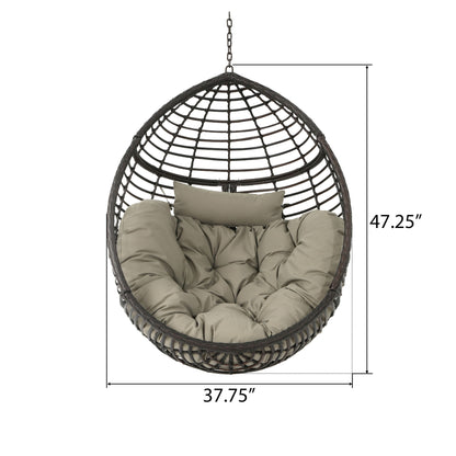 The Hanging Basket Chair with Metal Frame and Seat Cushion features an egg-shaped wicker design, beige tufted cushion and pillow, hangs by a chain, and measures 47.25" tall by 37.75" wide.