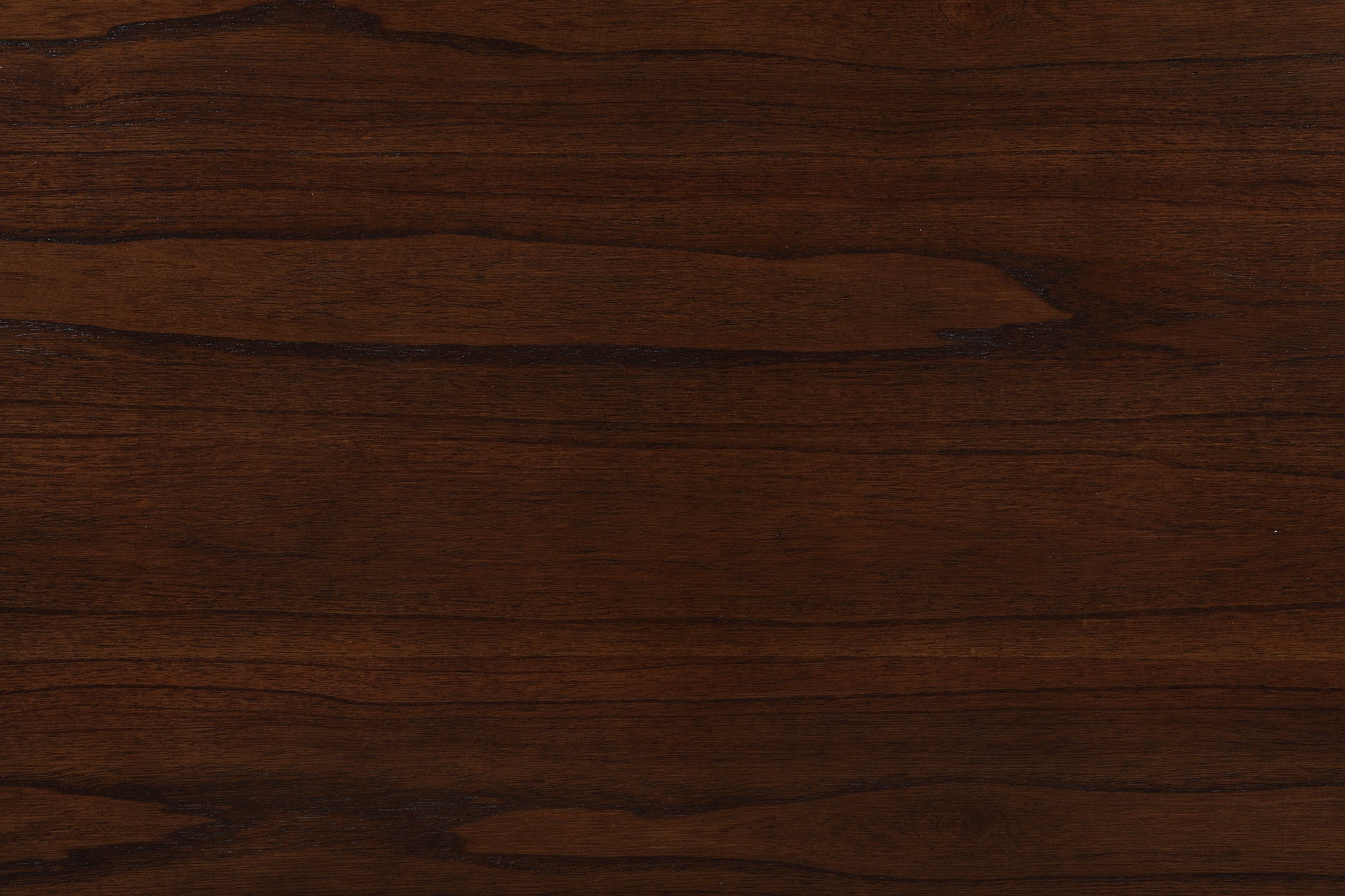 Close-up of the Graham dining table's dark brown wooden surface reveals its grain patterns and natural color variations, offering both texture and modern functionality with USB charging ports and shelves.