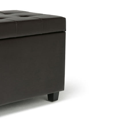 Close-up of the Cosmopolitan - Upholstered Storage Ottoman in dark brown leather with tufted detailing and black square legs. Only the corner, part of the side, and top are visible against a white background.