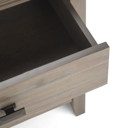 A close-up of the Artisan - Handcrafted Bedside Table shows an open wooden drawer with a metal handle, revealing its empty interior and part of the surrounding cabinet.