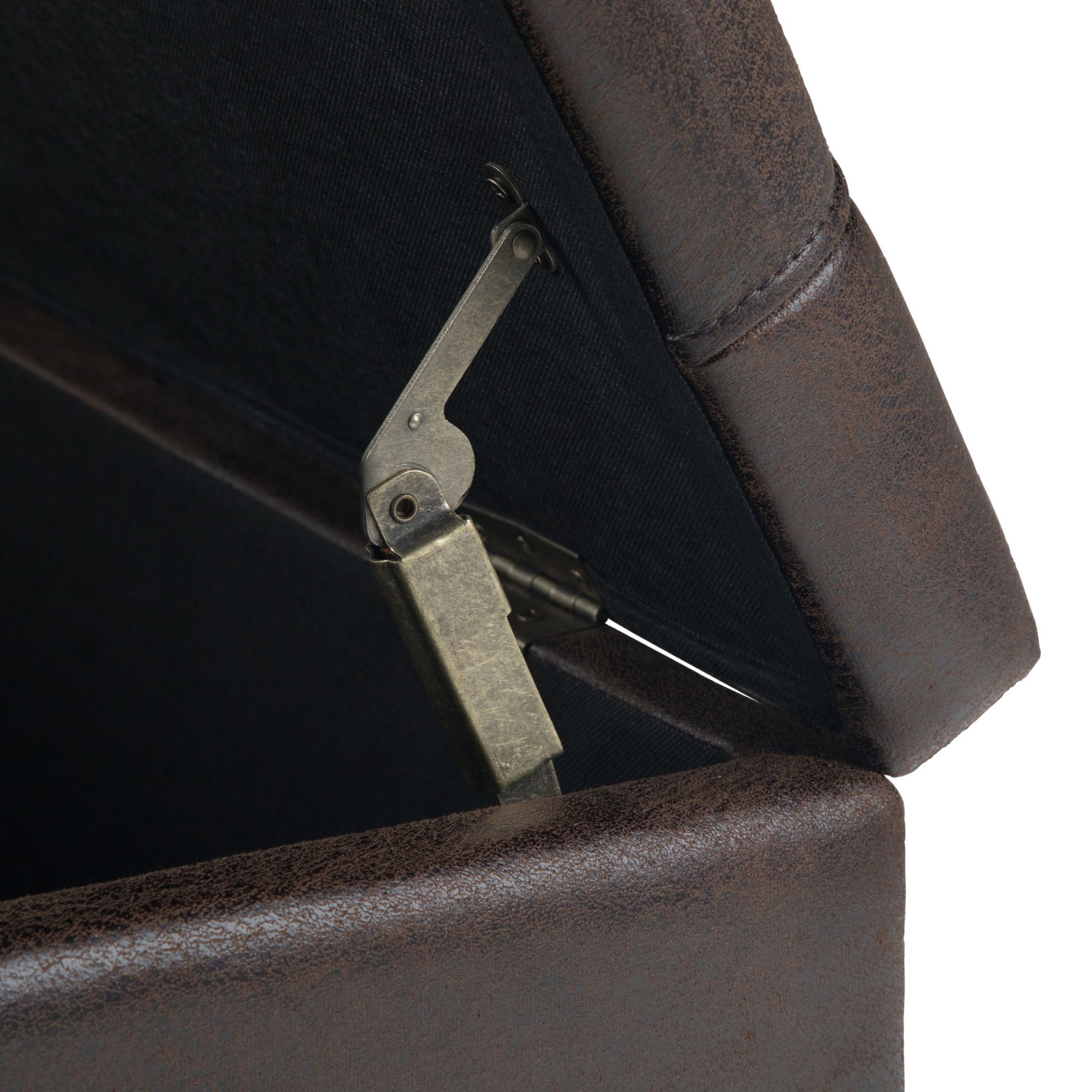 Close-up of the Harrison - Large Coffee Table Storage Ottoman in brown leather, shown with its lid open to reveal a metal hinge mechanism and a black fabric-upholstered interior.
