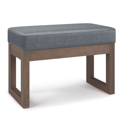 The Milltown Upholstered Ottoman Bench features a cushioned gray seat and a modern wooden frame with open, square legs.
